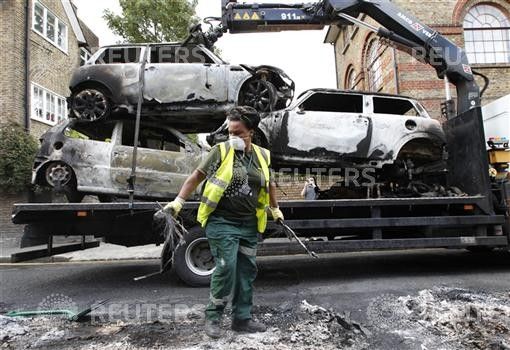 A council worker clears the remains of destroyed vehicles in Hackney, north London