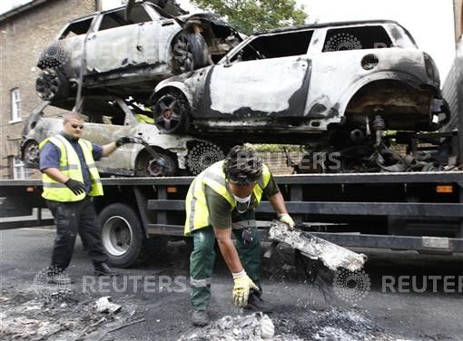 Council workers clear the remains of destroyed vehicles in Hackney, north London
