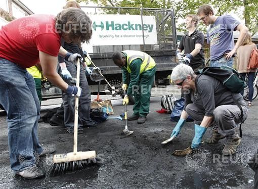 Part of a group of about 300 volunteers help clear the remains of destroyed vehicles in Hackney