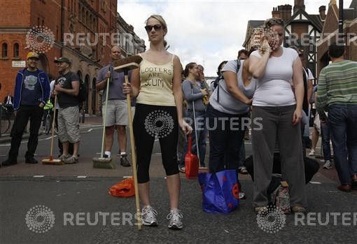 A woman poses for a photograph as volunteers wait to clear-up after overnight disturbances in Clapham Junction, in south London