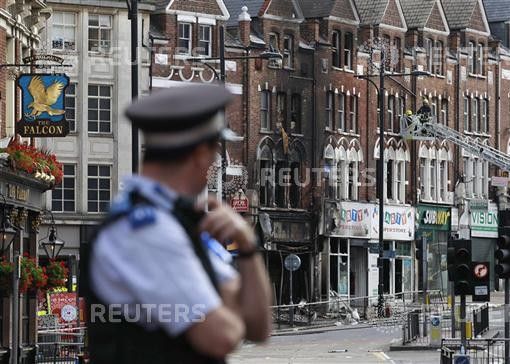 A police officers stands near a burnt out shop in Clapham Junction, in south London