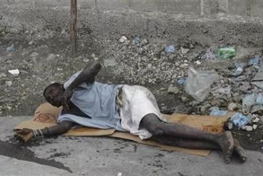 A Haitian resident suffering from cholera waits for help on a street at the slum of Cite-Soleil in Port-au-Prince