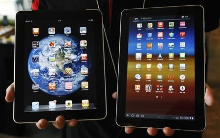 An employee of South Korean mobile carrier KT holds a Samsung Electronics' Galaxy Tab 10.1 tablet and Apple Inc's iPad tablet as he poses in Seoul