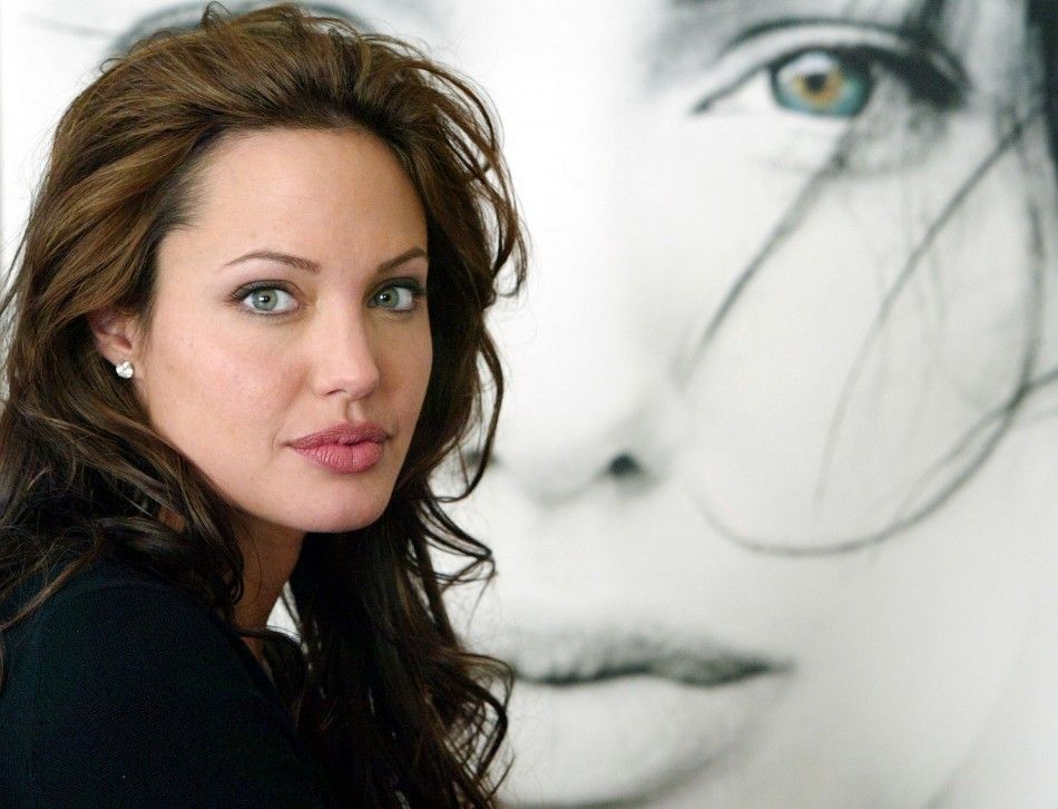 ACTRESS ANGELINA JOLIE POSES NEXT TO A POSTER FOR HER NEW FILM.