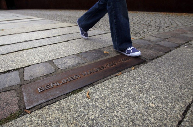 A person walks across plaque that shows where Berlin Wall used to stand at Berlin Wall memorial site in Bernauer Strasse