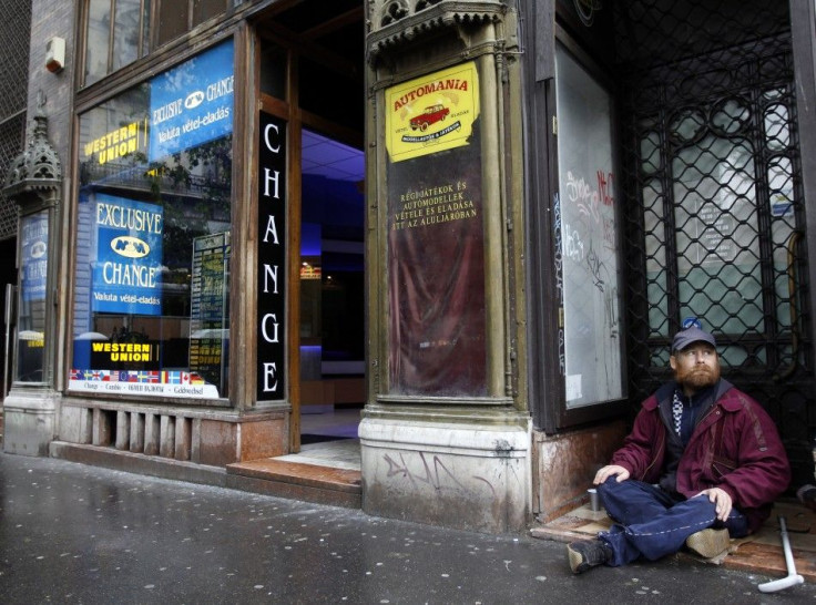A homeless man begs for money next to a money changer in Budapest
