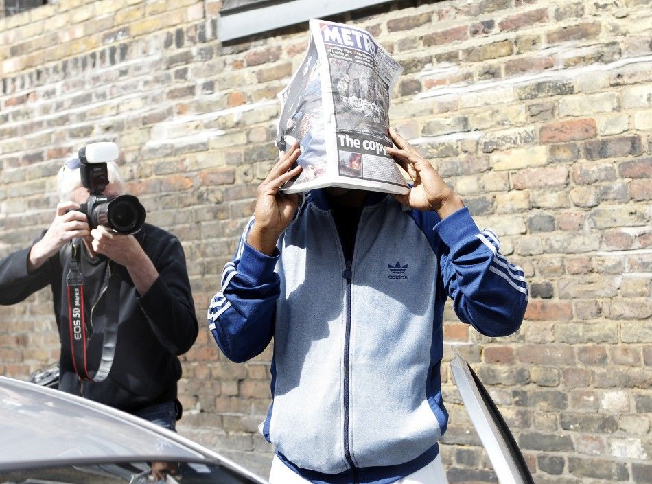 Primary school worker Alexis Bailey R attempts to shield his face as he leaves Highbury Magistrates court after he pleaded guilty to burglary with intent to steal in London August 10, 2011.
