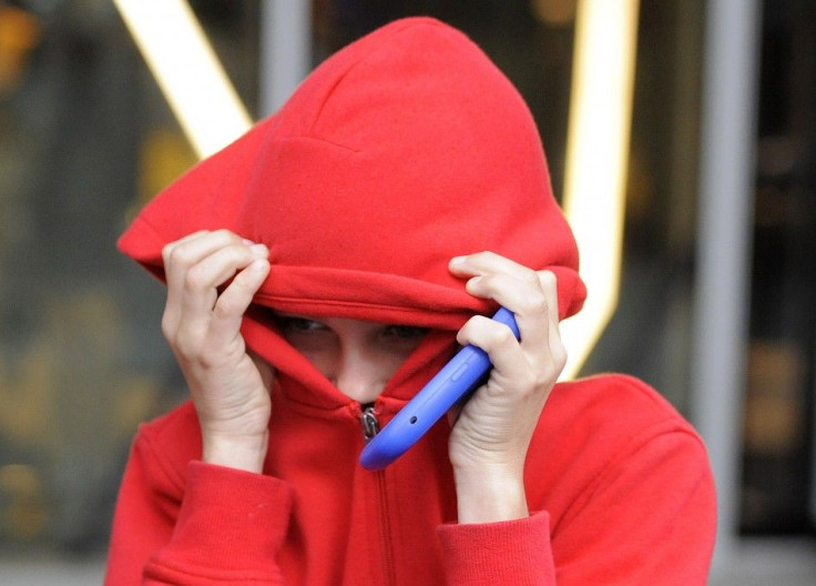 A 12 year-old boy shields his face as he leaves Manchester magistrates' court after admitting burglary, during the recent riots in Manchester, northern England August 11, 2011.