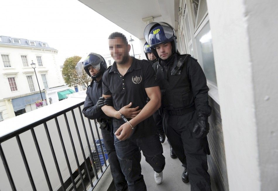 Police officers lead away a man following a raid on a property in Pimlico, London August 11, 2011.