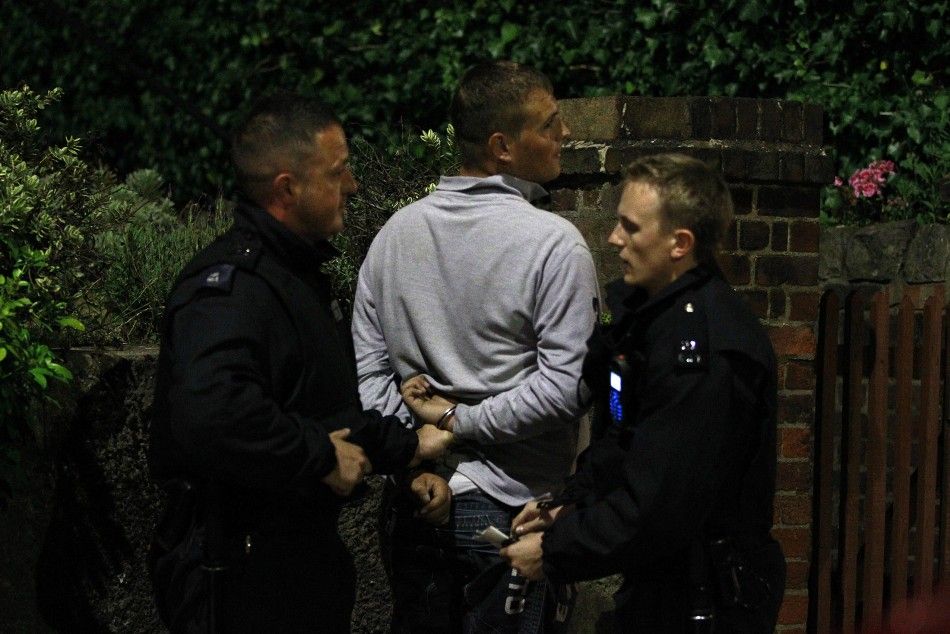 Police officers detain a man in Eltham, south London August 10, 2011