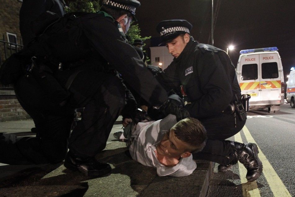 Police officers detain a man in Eltham, south London August 10, 2011. 