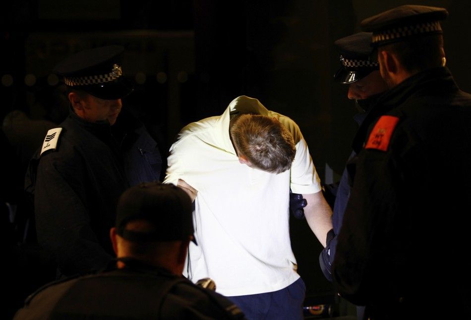Police officers restrain a man, who was part of a group that gathered to repel possible rioters and looters, as he struggles to avoid having his picture taken in Eltham, southeast London, August 10, 2011