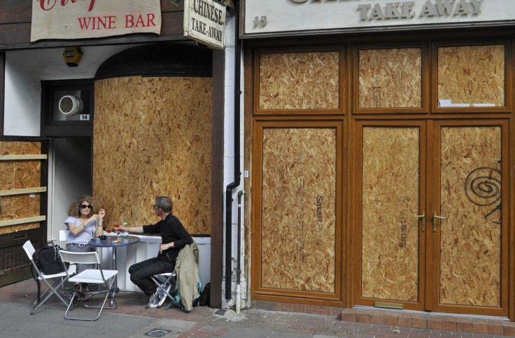 A couple drink at a boarded up wine bar in Ealing, west London