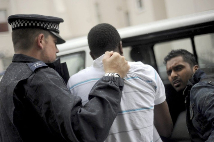 Police officers lead away a man following a raid on a property in Pimlico. London.