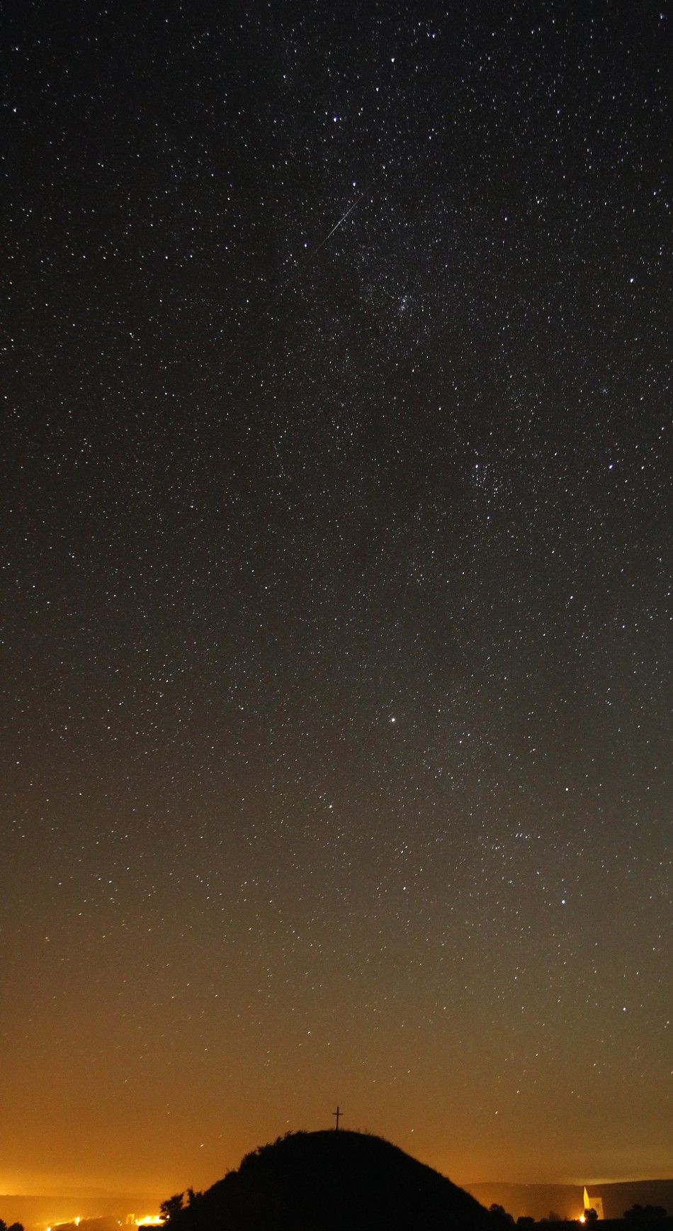 A meteor streaks past stars in the night sky over Leeberg hill in Grossmugl