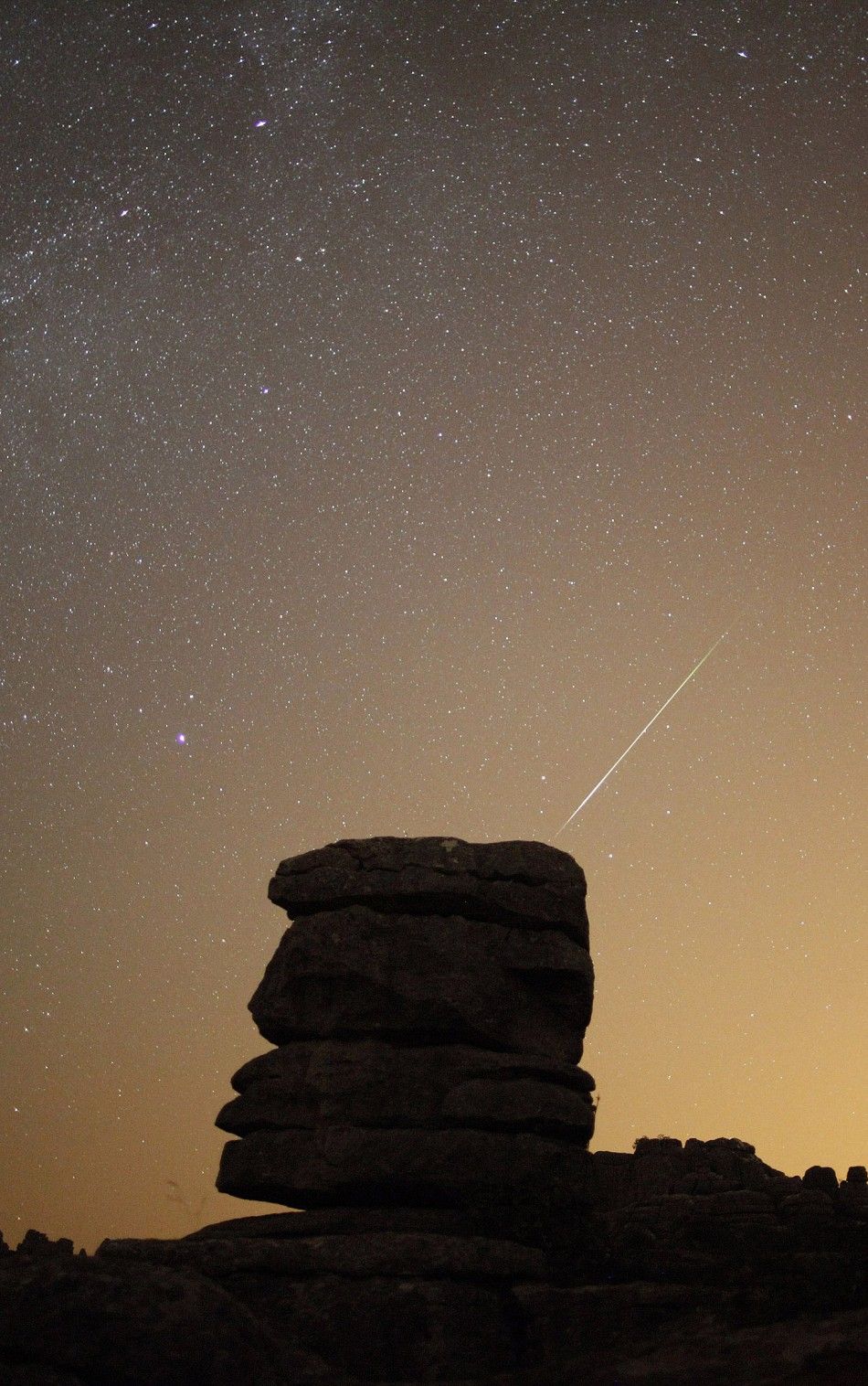 A meteor streaks past stars in the night sky over El Torcal nature park reserve in Antequera