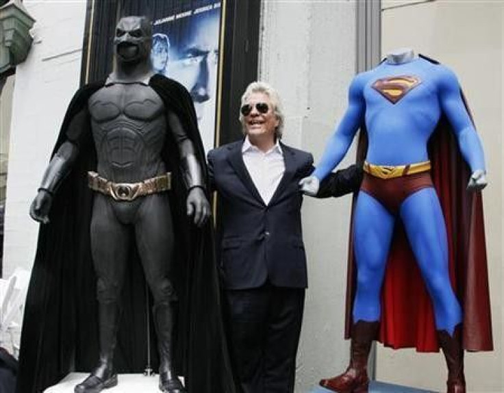 Film producer Jon Peters poses with a Batman (L) and Superman (R) costume after ceremonies unveiling his star on the Hollywood Walk of Fame in Hollywood