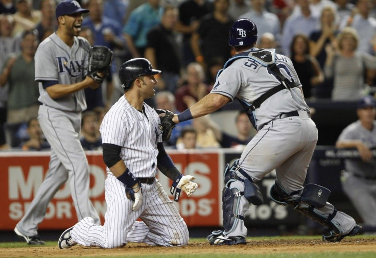 New York Yankees Nick Swisher reacts to being tagged out at home by the Tampa Rays catcher Kelly Shoppach in New York
