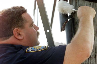 POLICEMAN INSPECTS VANDALIZED TELEPHONE CABLE IN BROOKLYN.