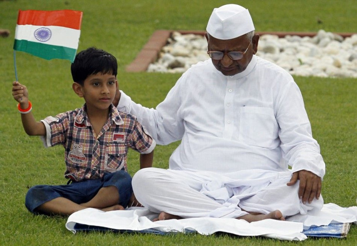 Boy holds Indian national flag as he sits next to veteran social activist Hazare at Mahatma Gandhi memorial at Rajghat in New Delhi