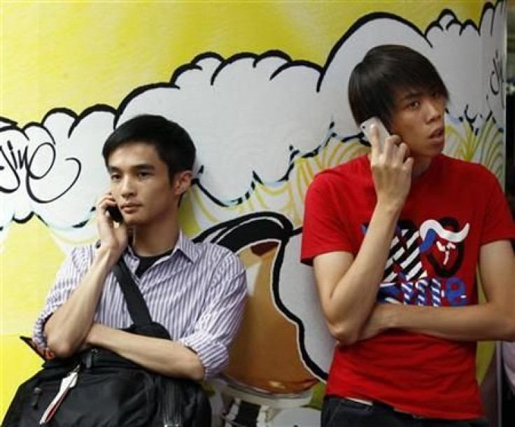 Two men use mobile phones as they wait outside a department store in Hong Kong