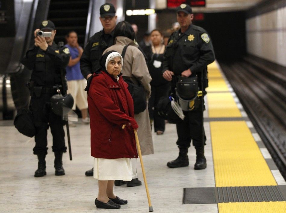 A nun waits for a train as police are pictured on the platform during a demonstration at the BART Civic Center Station in San Francisco
