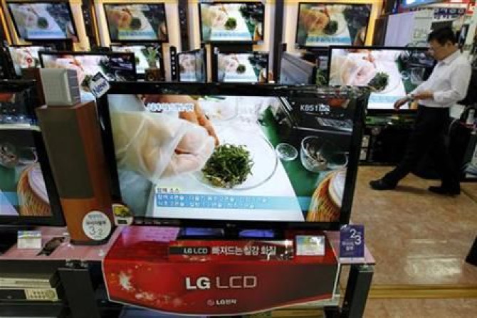 An employee of an electronics shop works behind an LG Electronics&#039; LCD television set in Seoul