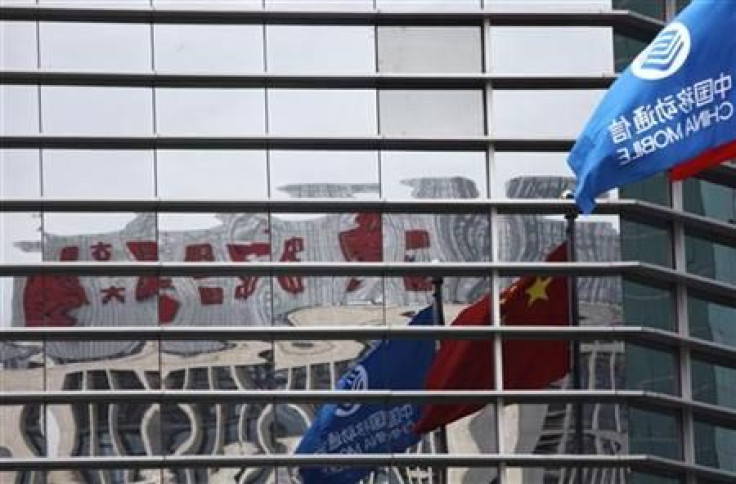 A China Mobile company flag and the Chinese national flag are reflected in the windows of the China Mobile building in central Beijing