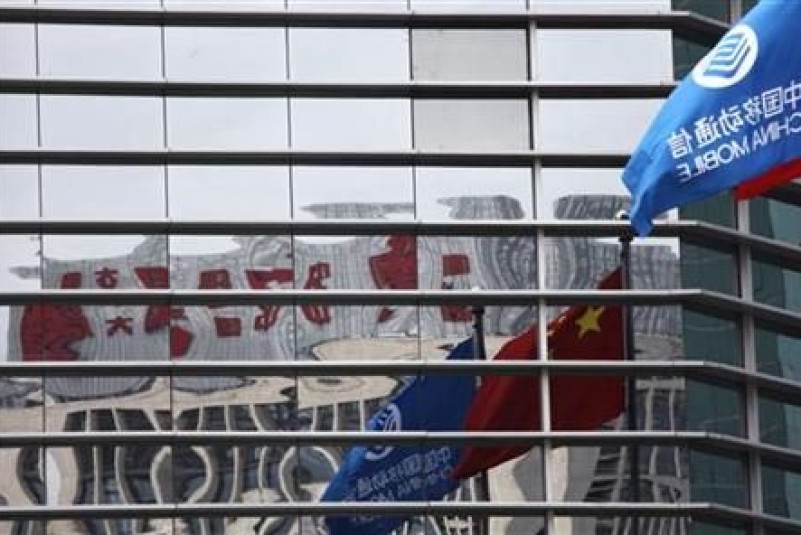 A China Mobile company flag and the Chinese national flag are reflected in the windows of the China Mobile building in central Beijing