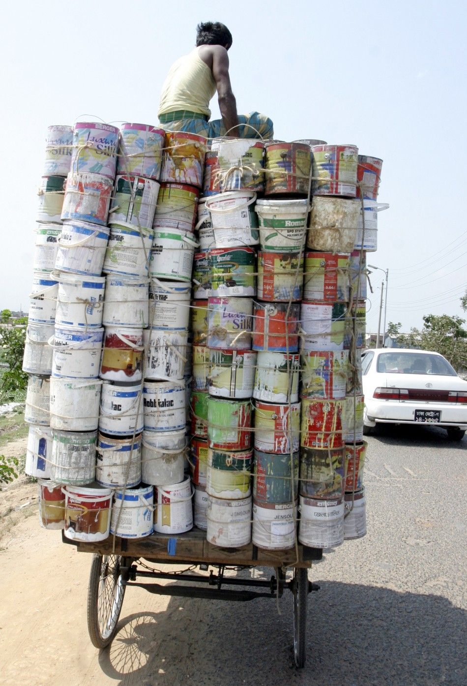A man transports used pots of paints to sell in a market in Dhaka