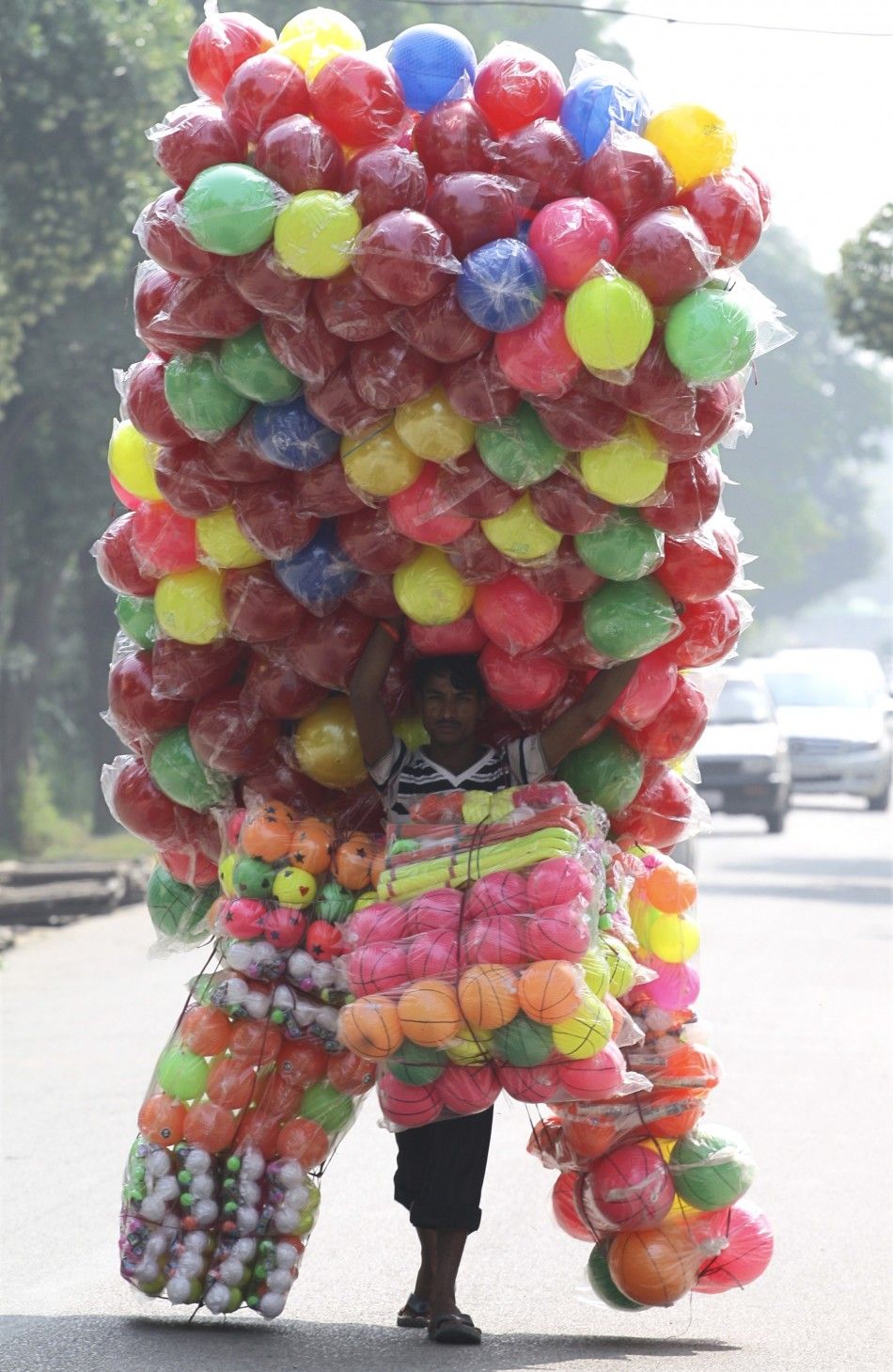 A vendor carries plastic balls for sale as he walks down the streets of Noida