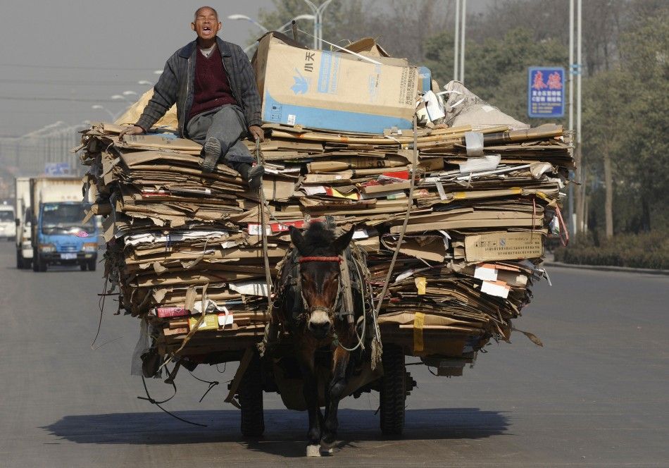 A man yawns while riding on a donkey cart loaded with recyclable materials in Changzhi