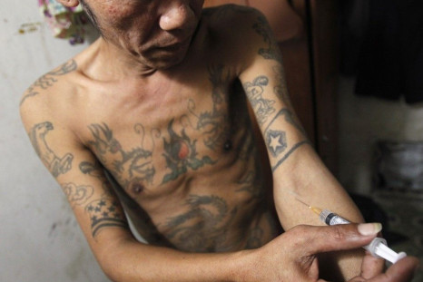 A Man , injects a syringe filled with heroin in his rented room in Hanoi