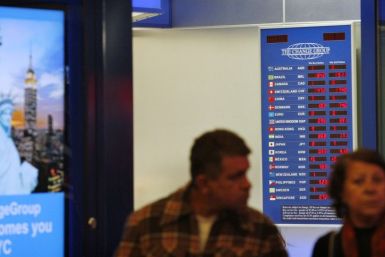 People walk past a board displaying exchange rates in a money exchange house at Times Square in New York