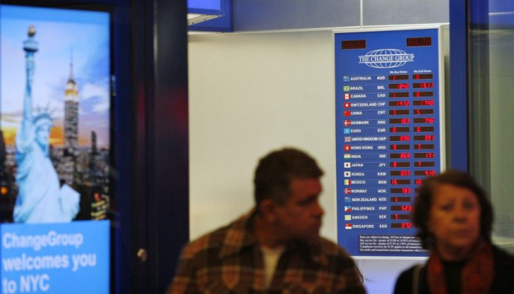 People walk past a board displaying exchange rates in a money exchange house at Times Square in New York