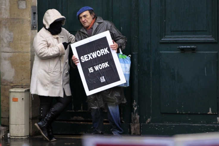 Prostitute wearing a mask speaks with an activist as they attend a demonstration ahead of vote on a symbolic resolution to abolish prostitution at the National Assembly in Paris