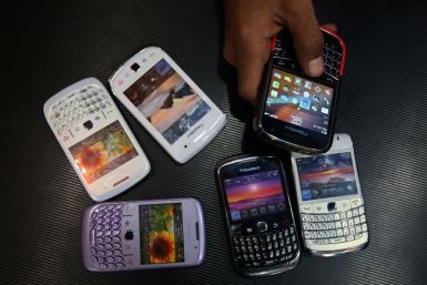 A salesman displays a Blackberry mobile phone to customers next to dummy handsets at a shop in Jammu