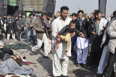A man carries a wounded boy after a suicide blast targeting a Shi&#039;ite Muslim gathering in Kabul