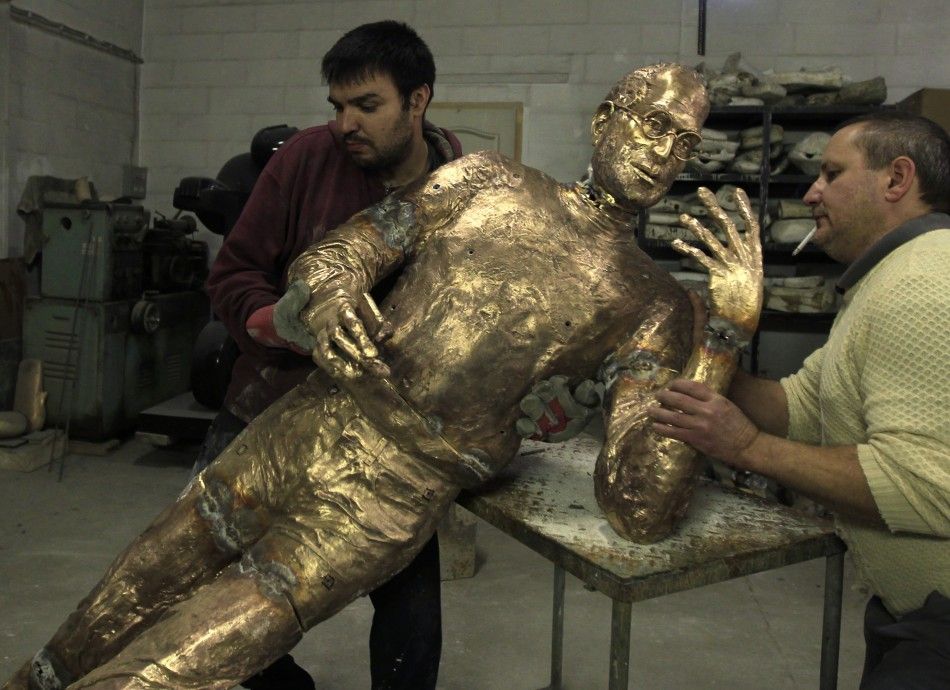 Assistants of Hungarian sculptor Erno Toth adjust his latest work, a bronze statue of late Apple CEO Steve Jobs, in Budapest