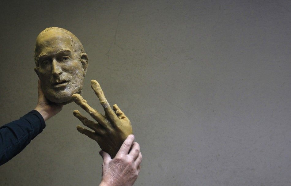 Hungarian sculptor Erno Toth holds up a face and a hand of a wax model for a new bronze statue of late Apple co-founder Steve Jobs in Budapest