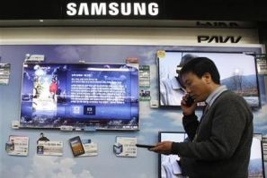 A salesman talks on his mobile phone as he walks past Samsung Electronics&#039; LED television displays at an electronics store in Seoul April 29, 2011.