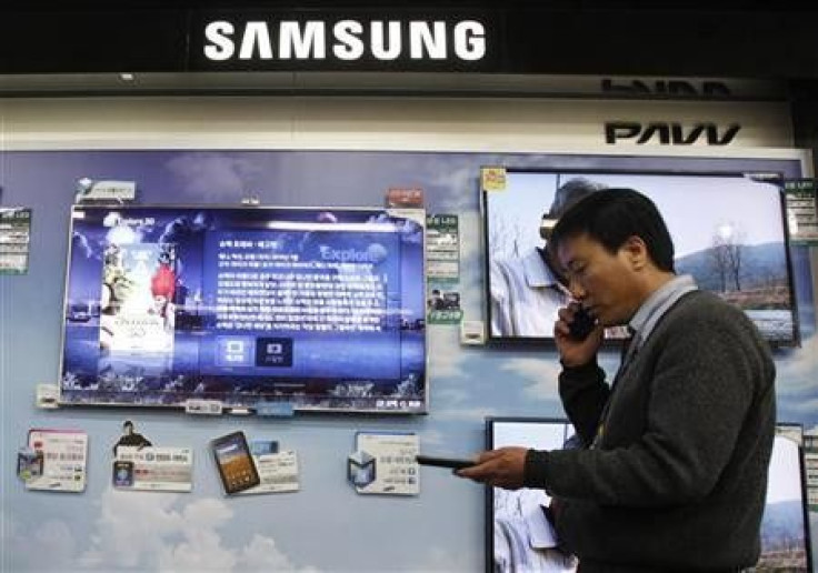 A salesman talks on his mobile phone as he walks past Samsung Electronics&#039; LED television displays at an electronics store in Seoul April 29, 2011.