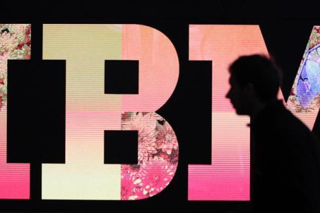 A man passes by an illuminated IBM logo at the CeBIT computer fair in Hanover