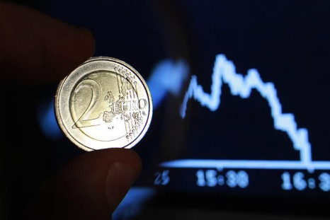 Photo illustration shows two euro coin through a magnifying glass near a picture of German share trading DAX index