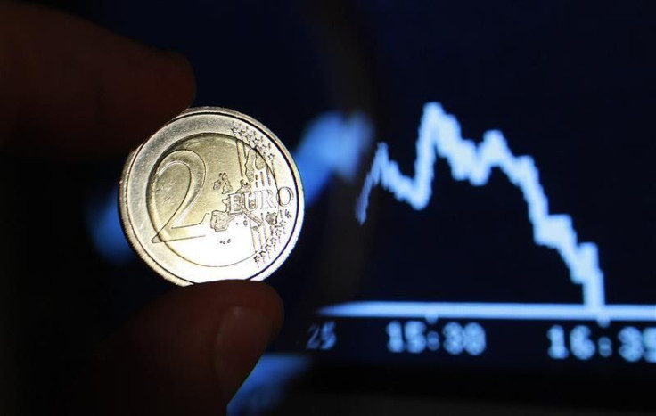 Photo illustration shows two euro coin through a magnifying glass near a picture of German share trading DAX index