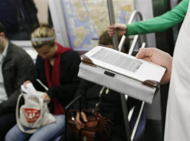 A commuter uses a Blackberry and a Kindle while riding the subway in New York