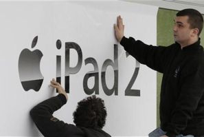 Workers stick-up a banner advertising the new iPad 2 at a computer store in Berlin
