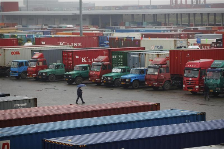 A man walks near trucks parked in a shipping container area at Shanghai Yangshan port
