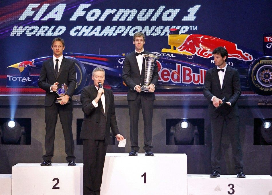 Red Bull Formula One driver Sebastian Vettel C of Germany, his teammate Mark Webber R of Australia and McLaren Formula One driver Jenson Button L of Britain stand on the podium while holding their trophies as an official speaks