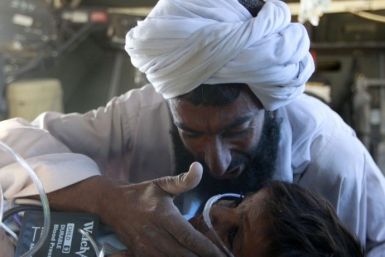 A father comforts his child who was injured in an explosion during a Medevac mission in southern Afghanistan's Helmand province
